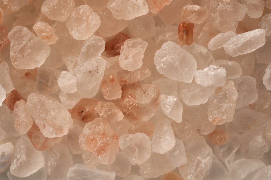 A high-resolution macro shot of translucent pink salt crystals, showcasing the natural mineral inclusions and crystalline structure